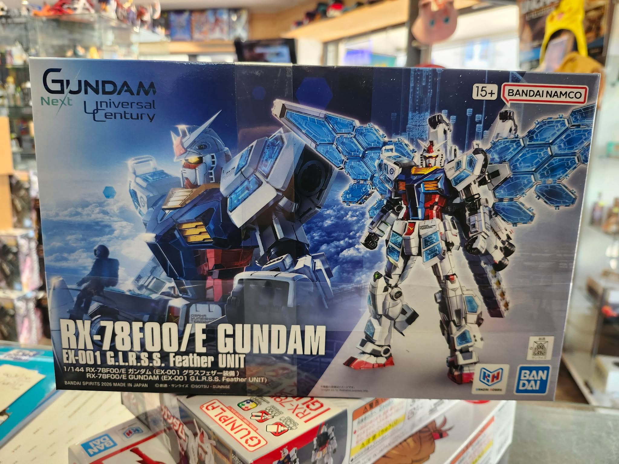 Photographie de la boîte de maquette Bandai représentant le HG Gundam RX-78 Feather, un modèle Gunpla 1/144 inspiré du célèbre RX-78 Gundam, posée dans une boutique.