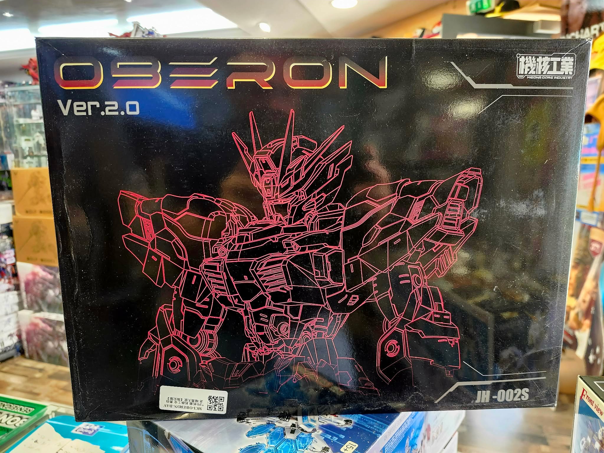 Photographie de la boîte de maquette représentant le HG Gundam Oberon Dark Angel Ver. 2.0, un modèle Gunpla au design sombre et original, présenté dans une boutique.